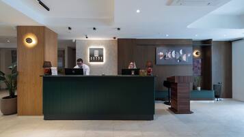 A modern reception desk with a wooden finish, a digital display, and a potted plant.