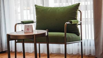 Una habitación con una silla verde acolchada y una pequeña mesa redonda con un letrero.