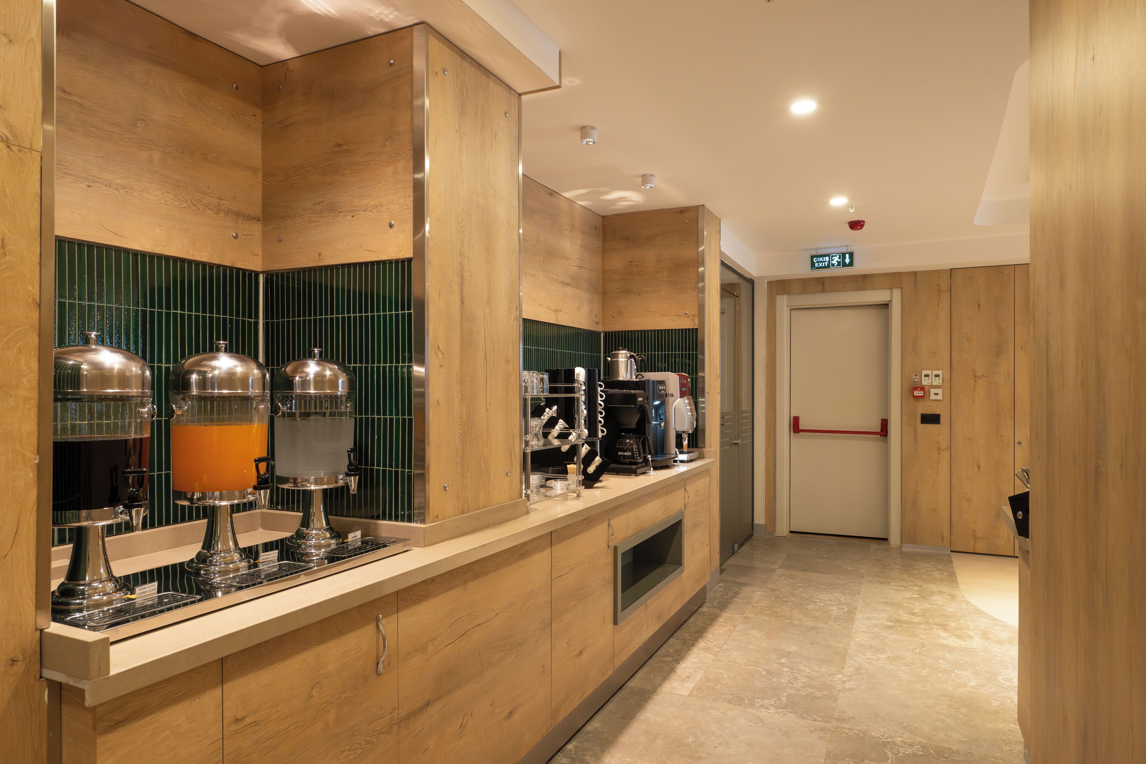 A modern kitchen with wooden cabinets, a coffee station, and a microwave.