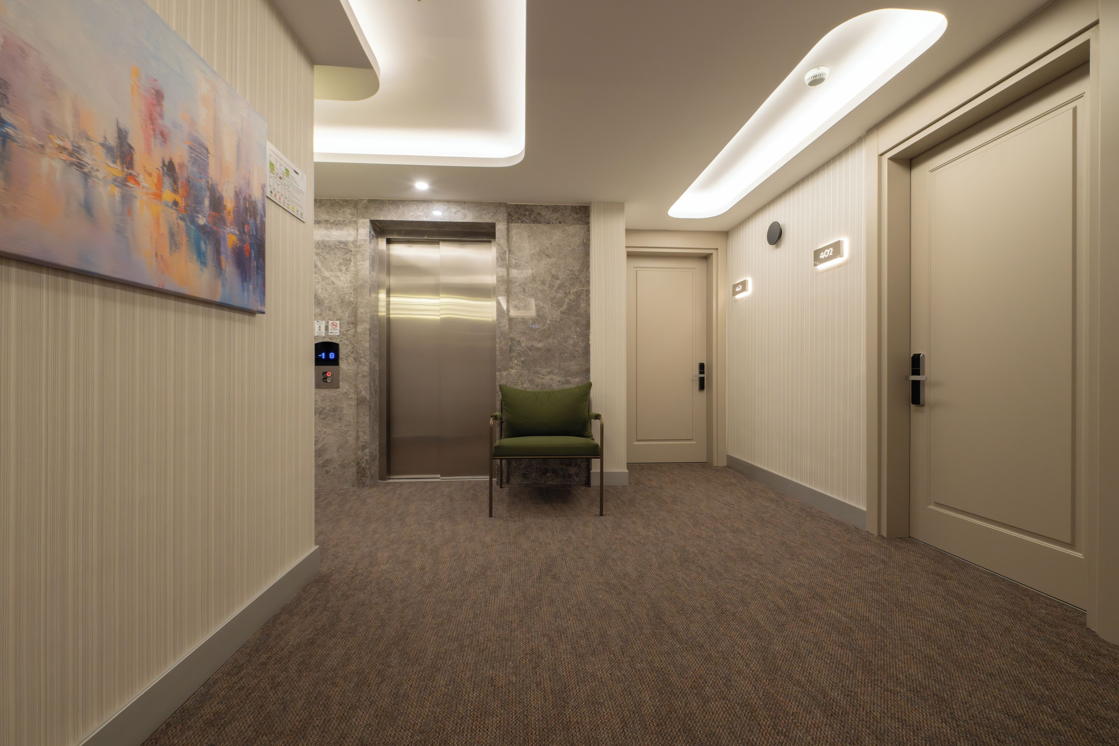 A hotel hallway with a green chair, an elevator, and a door marked "407".