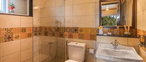 A bathroom with a toilet, shower, and sink.