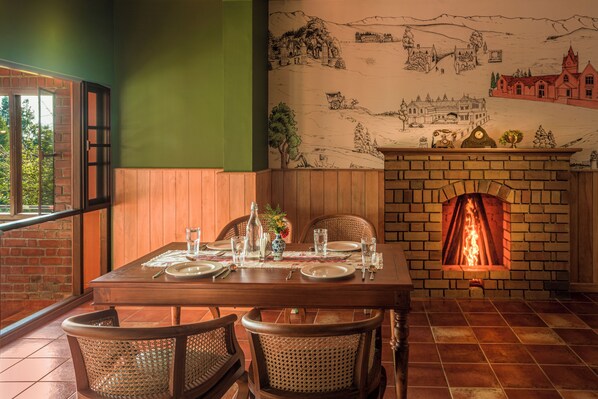 Un comedor con chimenea de ladrillo, un mural en la pared y una mesa dispuesta para cuatro personas.