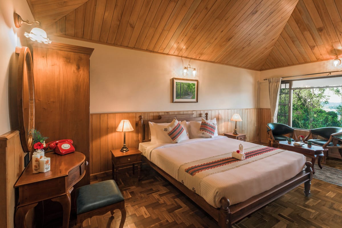 A wooden-paneled bedroom with a bed, bedside tables, a desk, and a chair.