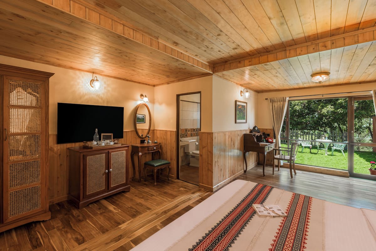 A wooden-paneled room with a flat-screen TV, a wooden cabinet, a desk, and a large sliding glass door leading to an outdoor area.