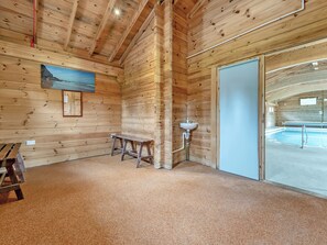Interior de una cabaña de madera con piscina, un banco y un lavamanos.
