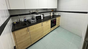 A kitchen with white cabinets, a black countertop, and a microwave.