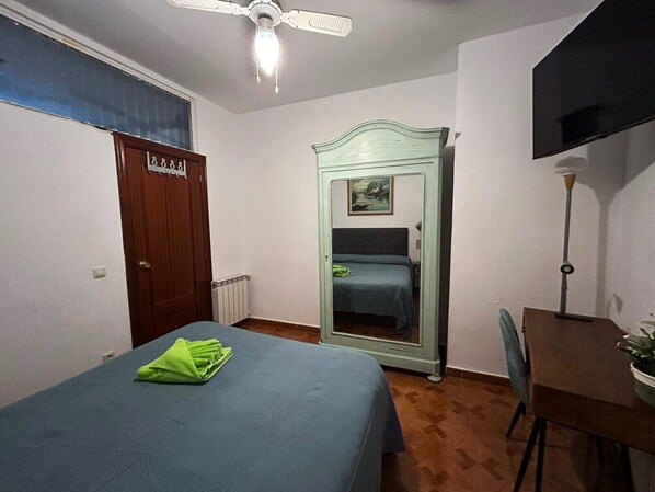 Un dormitorio con cama, armario, escritorio y televisor.