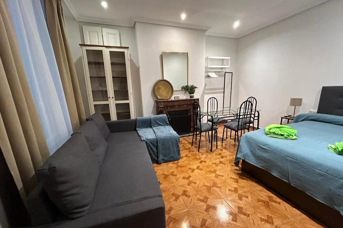 Een slaapkamer met een slaapbank, een bed, een eettafel met stoelen en een kledingkast.