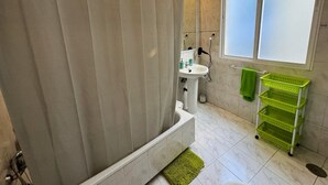 A bathroom with a shower curtain, a sink, a mirror, and a window.