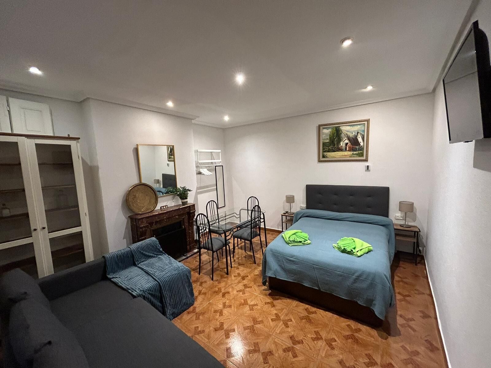 Une chambre à coucher comprenant un lit, un canapé, un bureau avec une chaise, une armoire et un tableau accroché au mur.