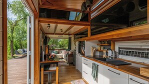 Une cuisine de taille réduite, dotée de meubles en bois, d’un plan de travail et d’une fenêtre donnant sur une terrasse.