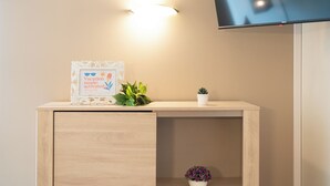 Un bureau en bois, orné d’une plaque encadrée, avec une plante en pot et un petit pot de fleurs.