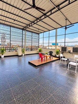 Terraza en la azotea de concepto abierto con asientos, plantas en macetas y ventanas amplias que ofrecen vistas a la ciudad.