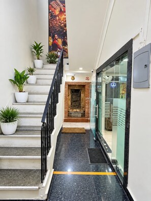 Una escalera con plantas en macetas, una chimenea de ladrillo y un ventanal que da a una habitación.