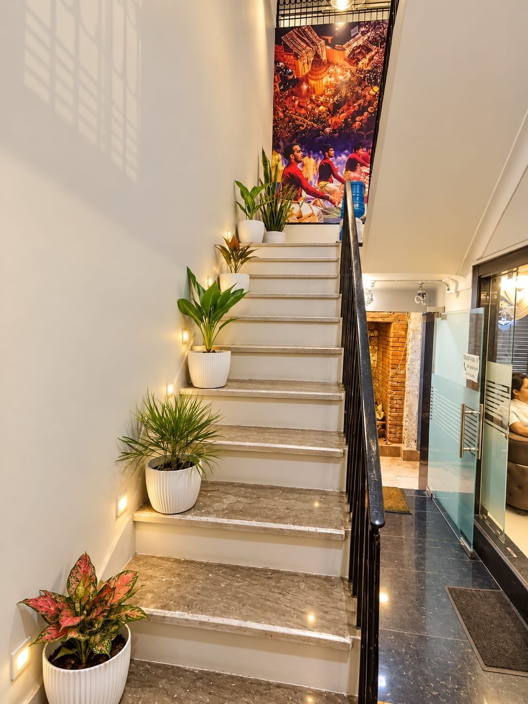 A staircase with multiple potted plants, a glass door entrance, and a wall-mounted artwork.