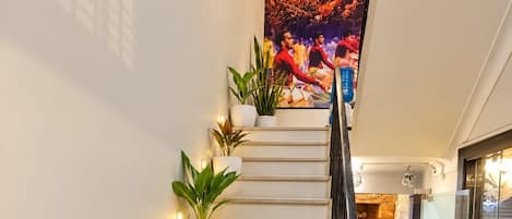 A staircase with multiple potted plants, a glass door entrance, and a wall-mounted artwork.