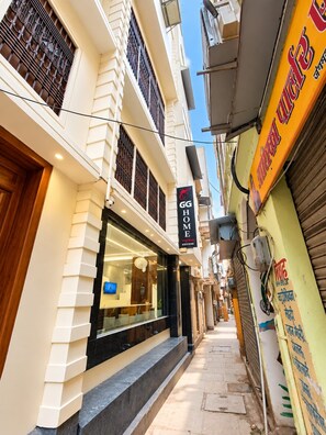 A narrow street with a hotel entrance, a closed shop, and a signboard with text.