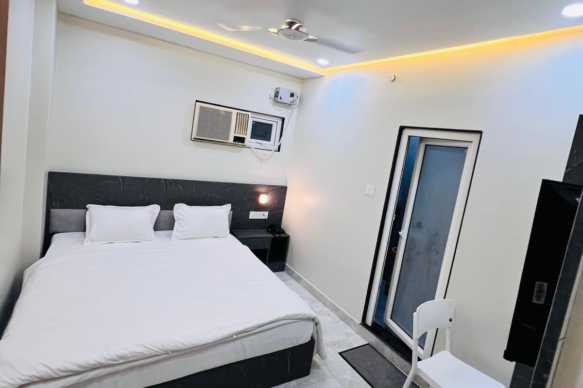 A modern bedroom with a large bed, a desk, a chair, and a TV.