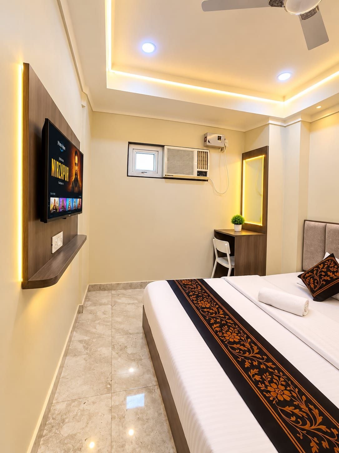 Habitación de hotel con cama, escritorio, televisor montado en la pared y aire acondicionado.