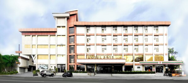 Ein mehrstöckiges Hotel mit einem gut sichtbaren Schild 'HOTEL BOSS', einem 7-Eleven Geschäft und einer Wellness- und Saunalage.