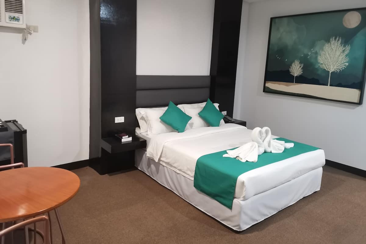 Habitació d'hotel amb llit, una tauleta de nit, una cadira i un quadre a la paret.