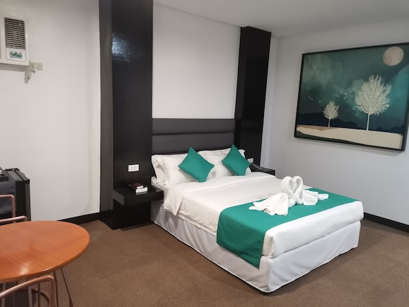 A hotel room with a bed, a nightstand, a chair, and a painting on the wall.