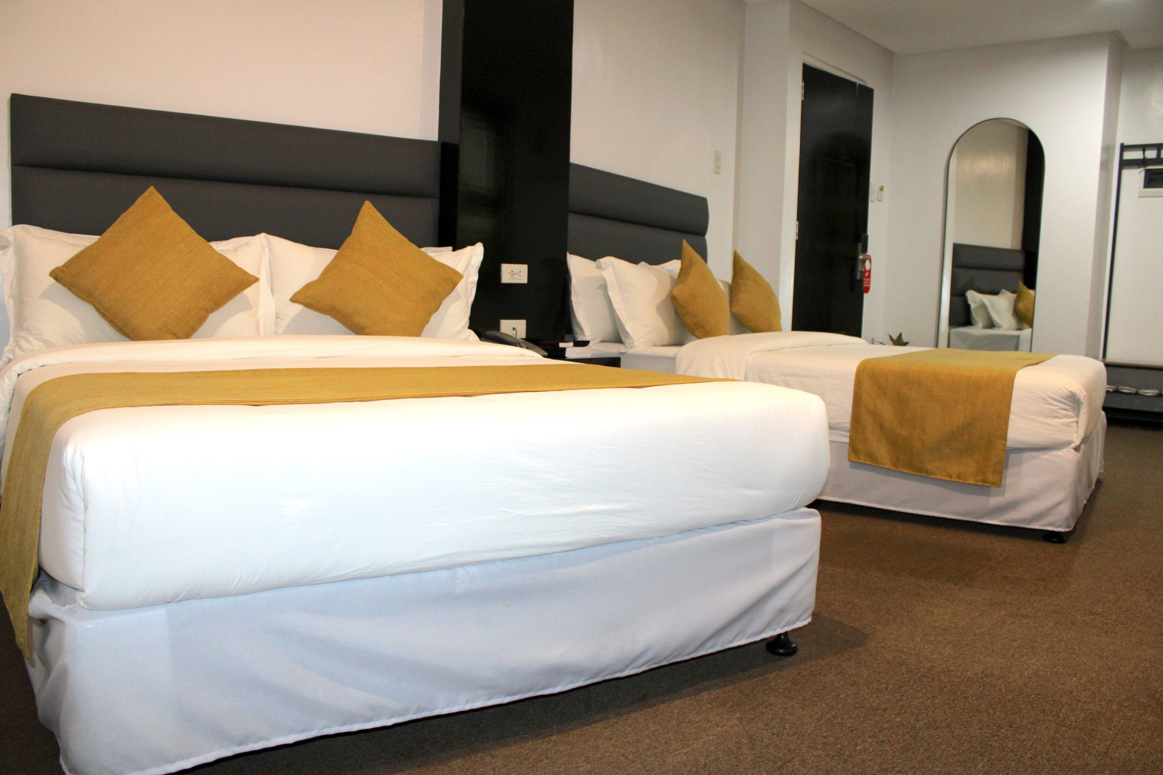 A hotel room with two beds, each with white bedding and brown throw pillows.