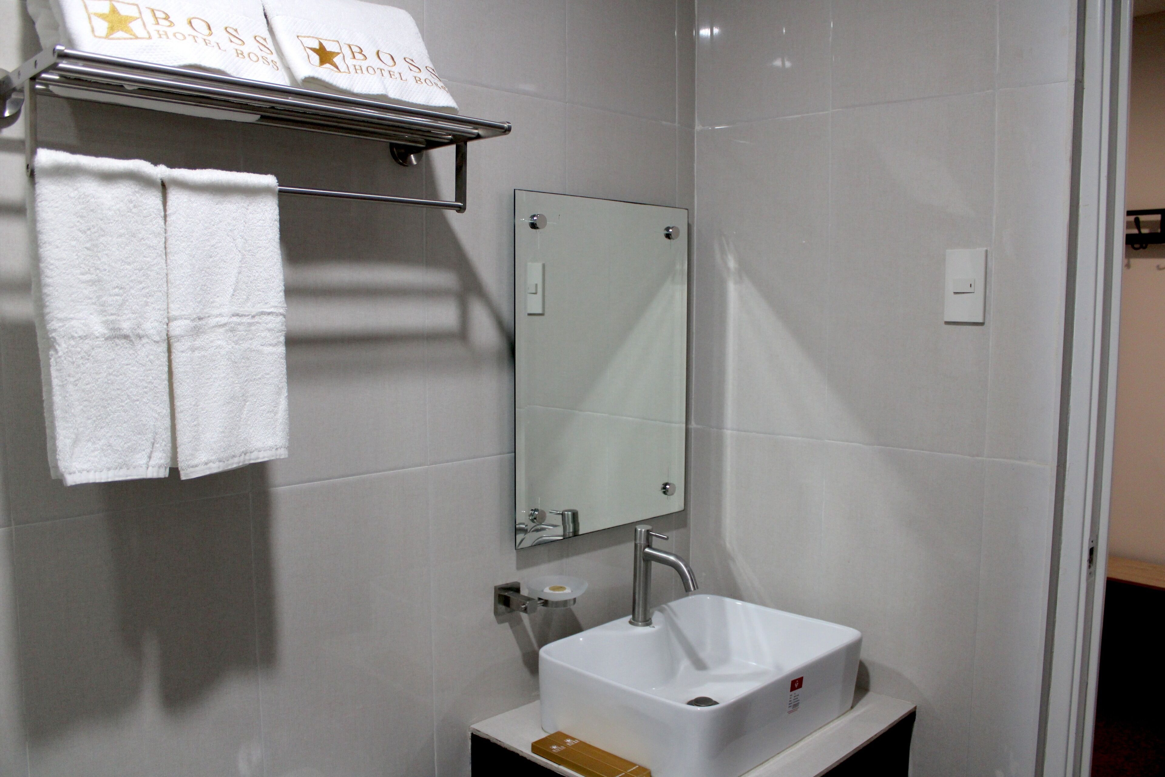 Une salle de bain avec un lavabo blanc, un miroir et un porte-serviettes avec des serviettes.