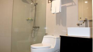 A modern bathroom with a glass-enclosed shower, a white toilet, and a black vanity with a mirror.