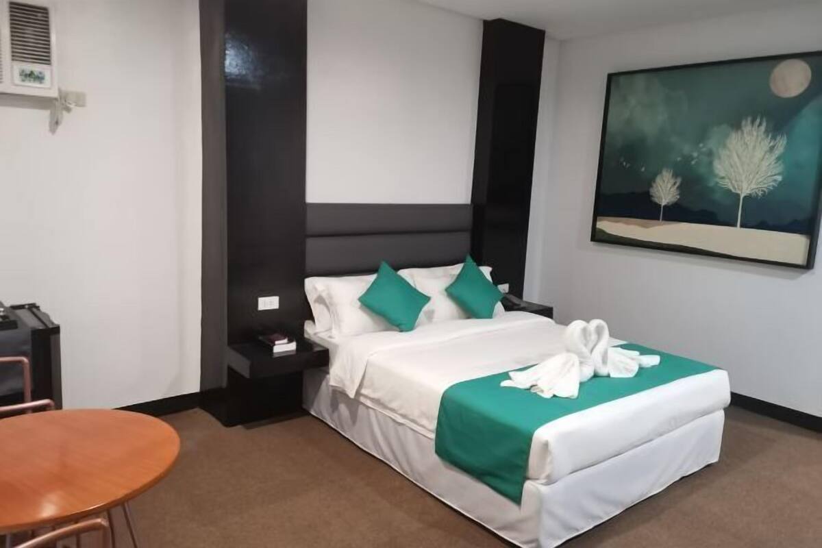 Habitació d'hotel amb llit, una vetustat, escriptori, cadira i un quadre a la paret.