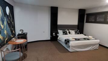 Habitación de hotel con cama, escritorio, silla y un cuadro en la pared.