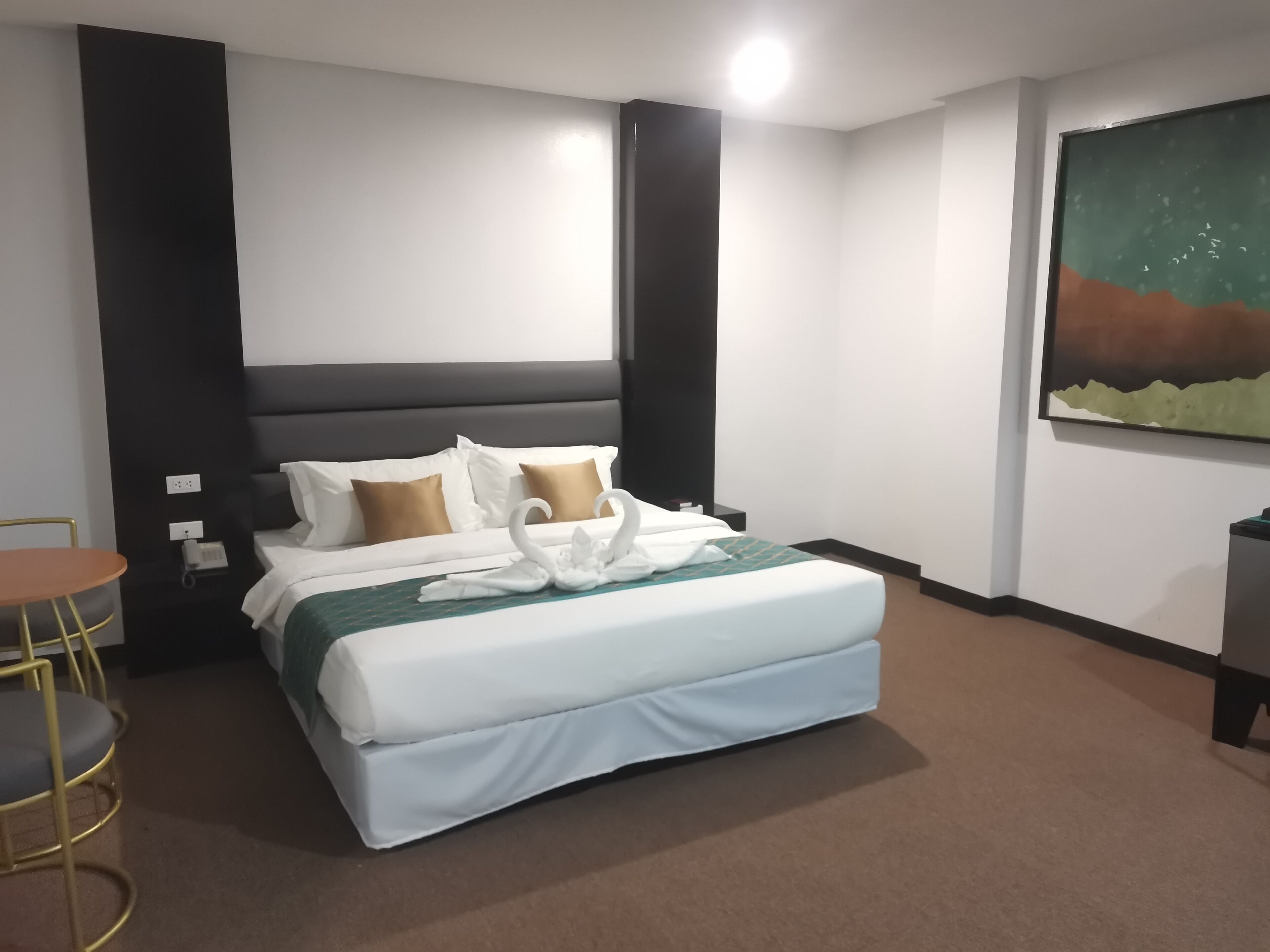 Una habitación de hotel con cama, una mesita y un cuadro en la pared.