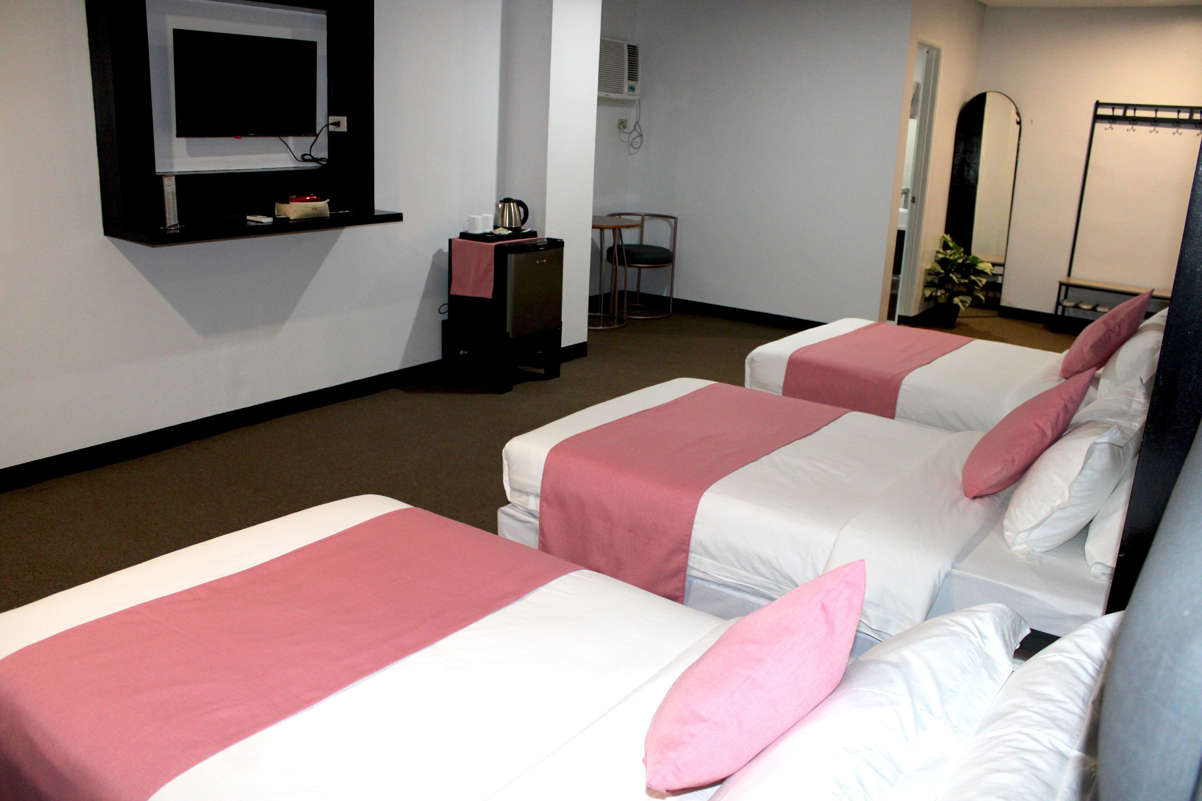 A hotel room with two beds, a TV, a desk, and a mirror.