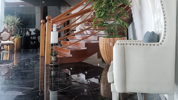 A modern interior with a polished marble floor, a wooden staircase with glass railings, and a white armchair with a decorative mirror. - Palette in Angeles, Pampanga near Clark International Airport (Formerly Boss Hotel) (Angeles City)