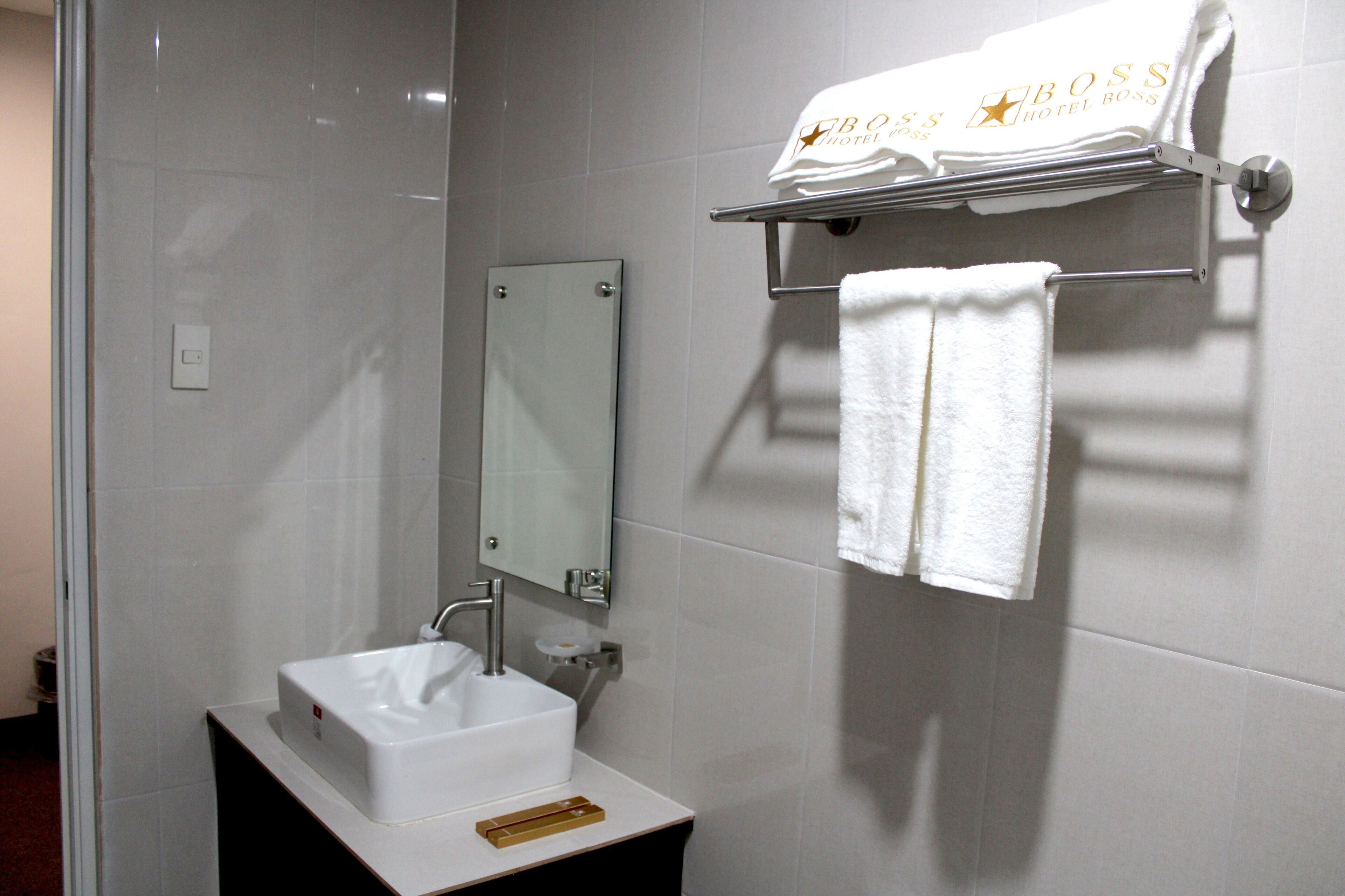 A bathroom with a white sink, a mirror, and a towel rack with a towel.
