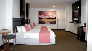 A hotel room with a large bed, a desk, a chair, and a painting of a landscape on the wall. - Palette in Angeles, Pampanga near Clark International Airport (Formerly Boss Hotel) (Angeles City)