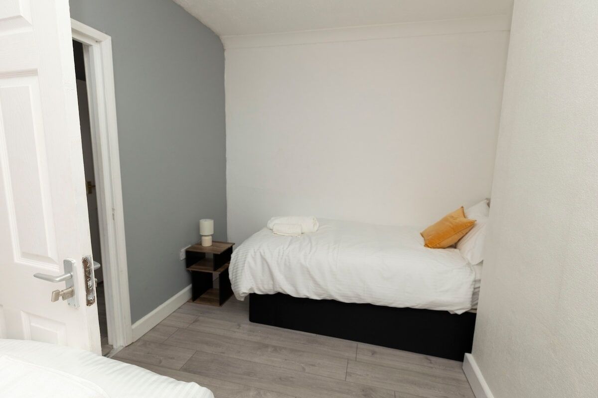 Quarto com uma cama, uma mesa de cabeceira e uma porta.