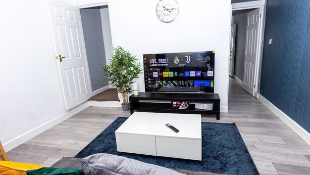 Un salon avec un téléviseur, une horloge et une plante.