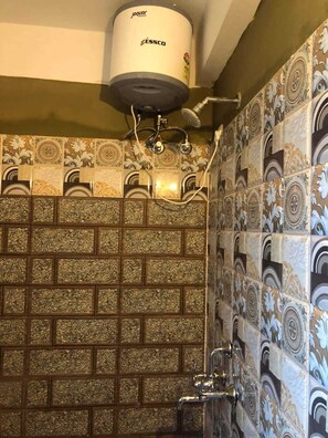 A bathroom with patterned tiles, a shower, and a toilet. - Zangmo Lee Baam (Gangtok)