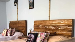 A bedroom with two wooden headboards, a bed with floral and vintage-style pillows, and two wall-mounted lamps. - Zangmo Lee Baam (Gangtok)