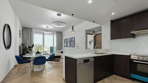 Una cocina moderna con lavavajillas, estufa y comedor con sillas y mesa.