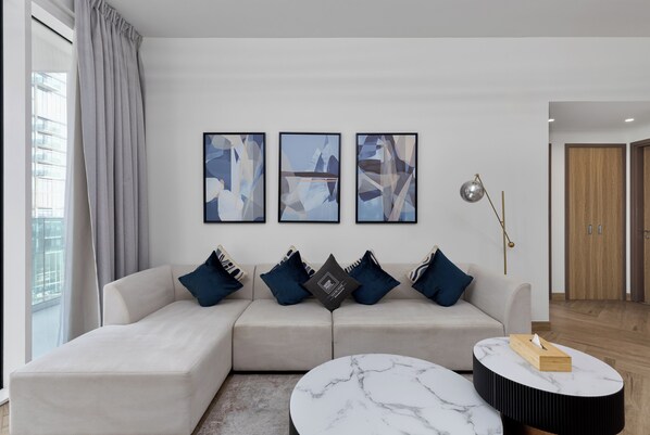 A modern living room with a sofa, a round coffee table, and abstract wall art.