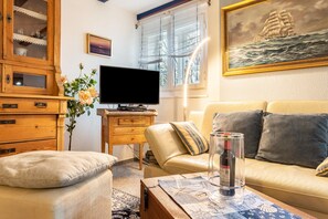 A living room with a television, sofa, and a painting of a ship on the wall. - Apartment 'Helgoland' with Shared Terrace, Shared Garden and Wi-Fi (Cuxhaven)