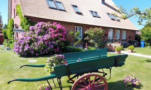 Un edificio con facciata in mattoni, una panchina verde e un grande cespuglio di fiori viola.