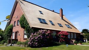 A two-story building with a sloped roof, a brick facade, and a small front entrance. - Apartment 'Kugelbake' with Shared Terrace, Communal Garden and Wi-Fi (Cuxhaven)