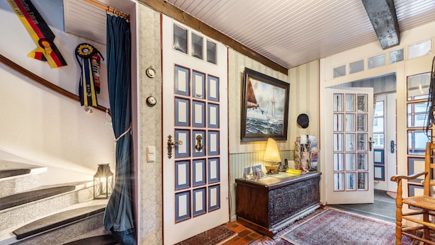 A staircase with a blue curtain, a framed painting, a lamp, and a wooden chair. - Apartment 'Kugelbake' with Shared Terrace, Communal Garden and Wi-Fi (Cuxhaven)