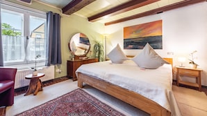 A bedroom with a large bed, a round mirror, a nightstand, a lamp, and a view of the outside. - Apartment 'Scharhörn' with Shared Terrace, Shared Garden and Wi-Fi (Cuxhaven)