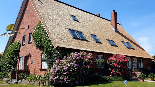 A two-story building with a sloped roof, multiple windows, and a sign indicating it is a bed and breakfast. - Apartment 'Scharhörn' with Shared Terrace, Shared Garden and Wi-Fi (Cuxhaven)