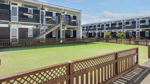 A multi-story hotel with balconies, a central staircase, and a green lawn area. - 4 Person Holiday Park Home in Glesborg (Glesborg)