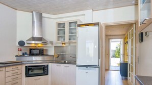 A modern kitchen with a built-in oven, microwave, and stainless steel range hood. There is a large refrigerator and wooden cabinets. - 4 Person Holiday Park Home in Glesborg (Glesborg)